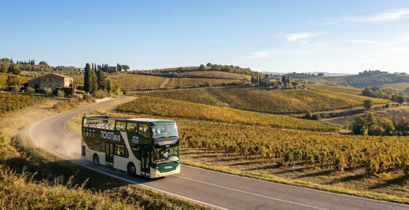 Un car Tootbus moderne traverse une route sinueuse au cœur des collines toscanes, entouré de vignobles dorés sous une lumière matinale
